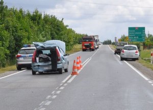 Zdjęcie przedstawia rozbity tył samochodu osobowego stojącego na jezdni. Na drodze pojazdy policji i straży pożarnej.